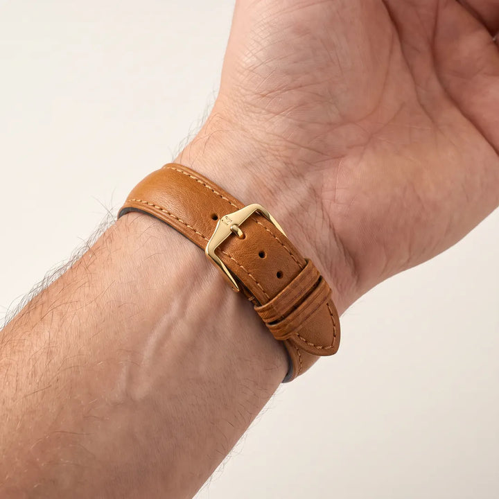 Hirsch Camelgrain Honey no-allergy leather watch band, 14mm, shown fastened on a man's inner wrist with polished gold pin buckle
