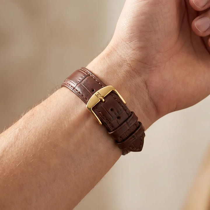 Man wearing the Duke brown alligator embossed leather watch band, inner wrist showing gold buckle with H engraving