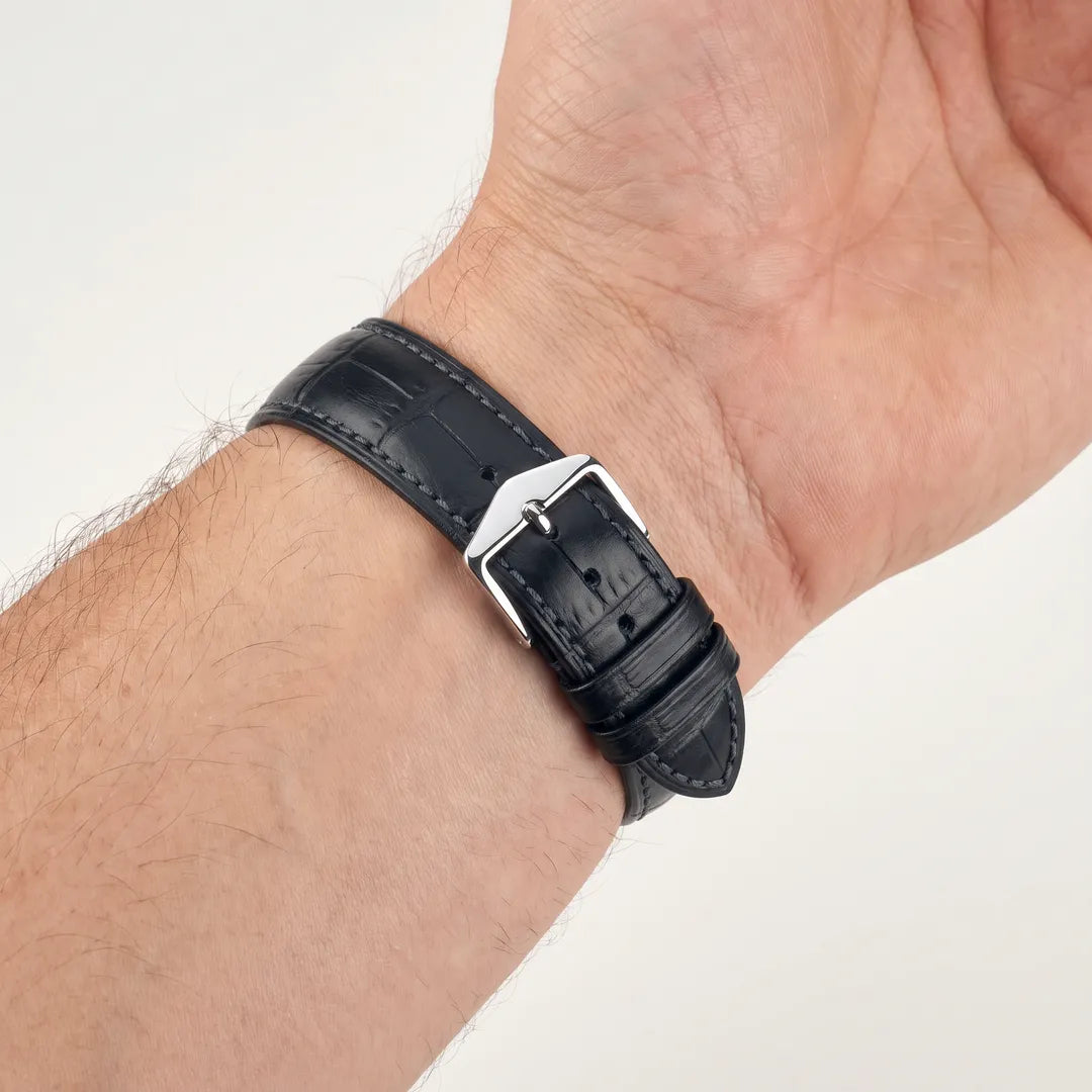 Hirsch Duke black alligator embossed leather watch band worn on a male wrist, inside view showing polished steel buckle