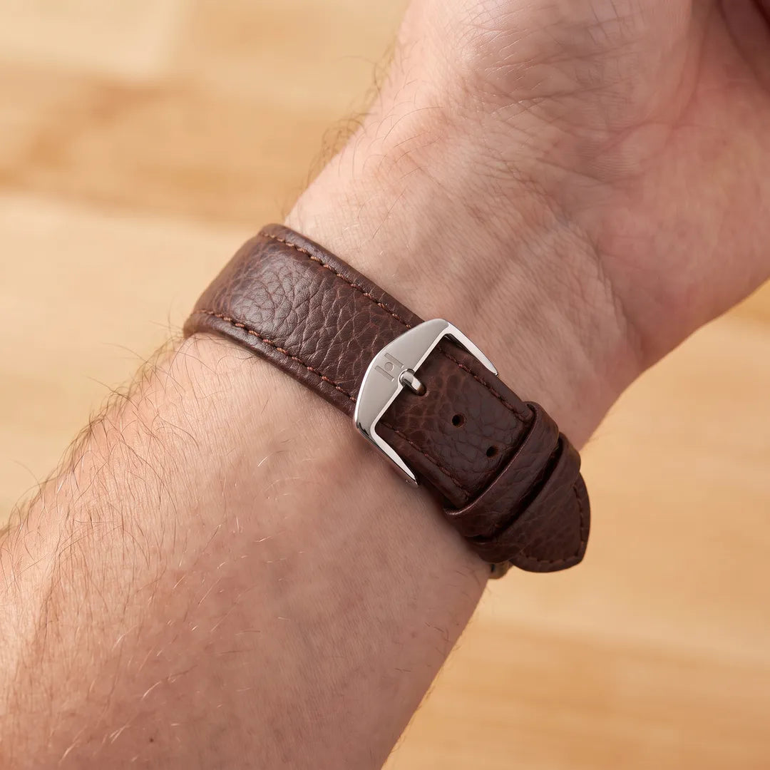 Man wearing the Hirsch Kansas brown buffalo-embossed leather watch band, inner wrist view showing the engraved H buckle