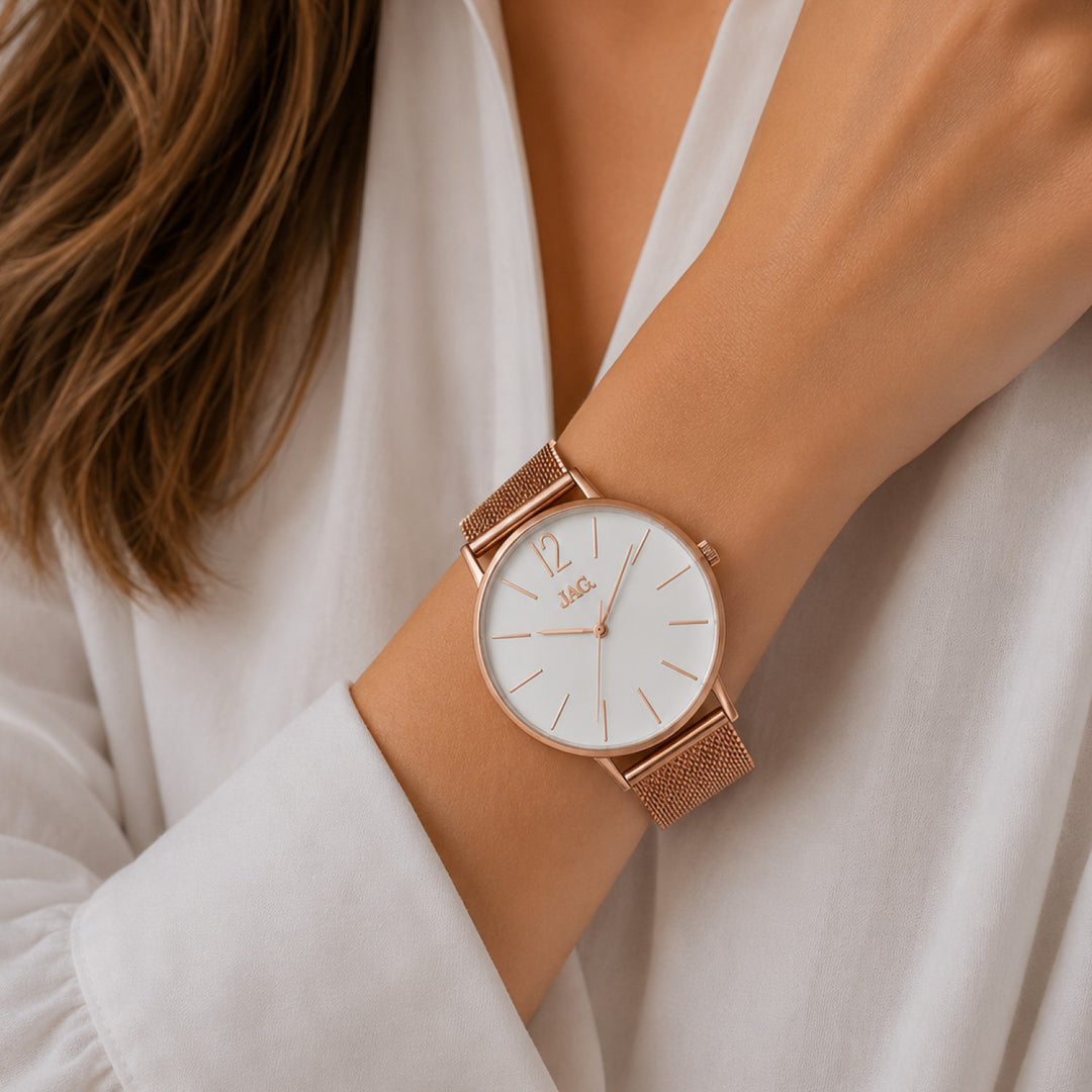 Close-up of a woman's wrist wearing a white JAG watch with a rose gold mesh strap.