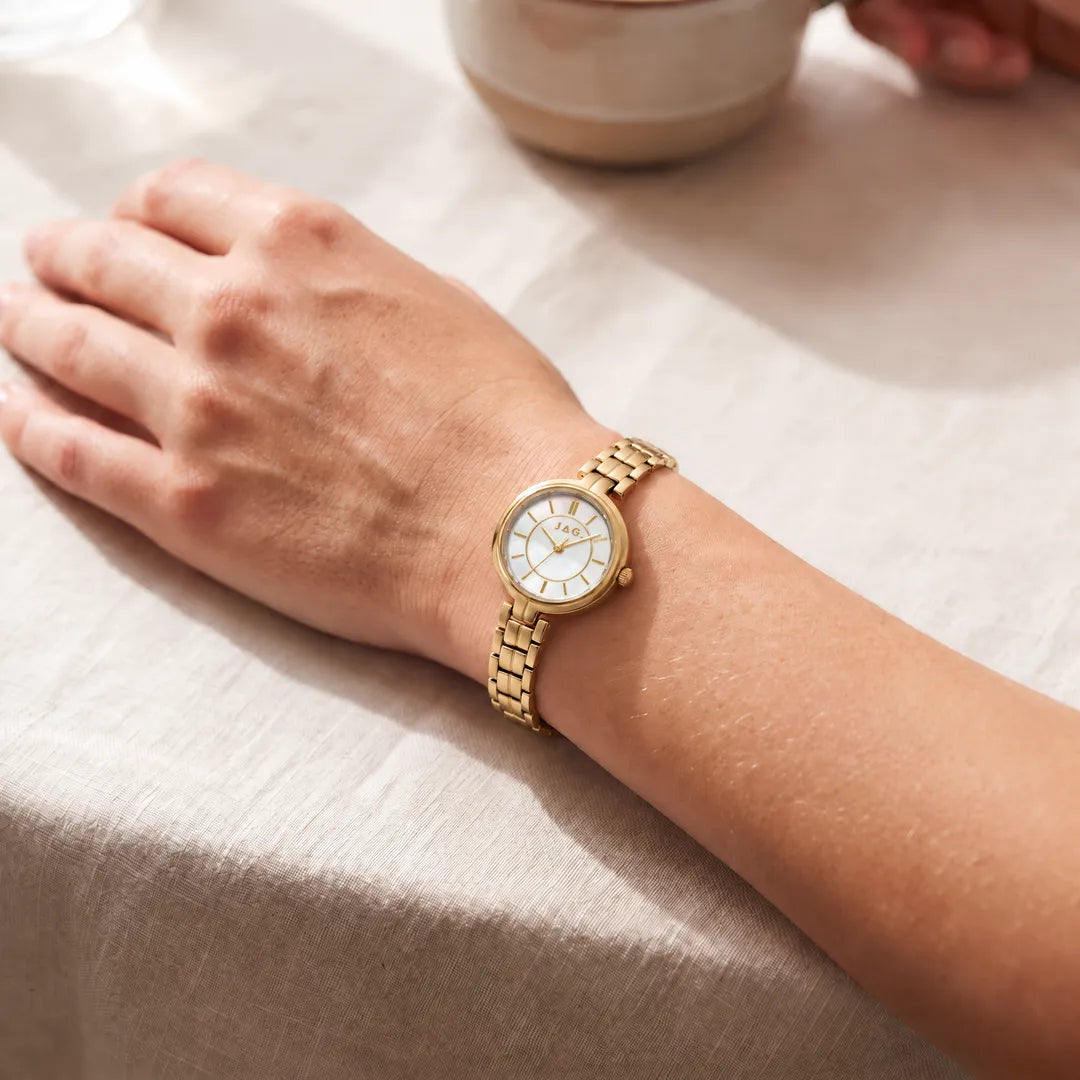 Jag Kelly womens 27mm gold watch with white mother-of-pearl dial worn on wrist
