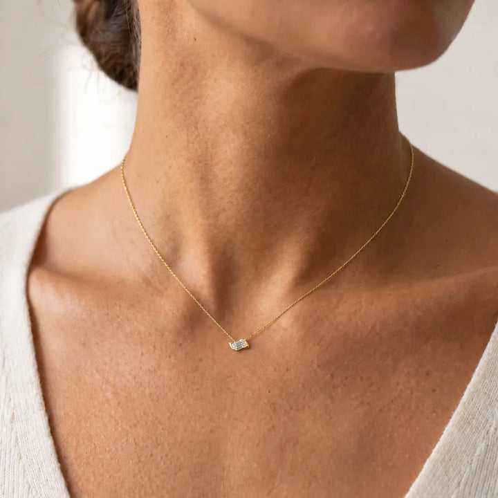 0.50ct Lab Grown Diamond Asterly Necklace in 9K Yellow Gold worn on a model, emerald-cut half-bezel pendant on a fine yellow gold chain at the base of the neck