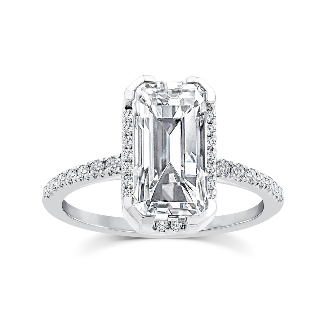 An emerald-cut diamond ring with a halo setting and a pavé-set diamond band, shown on a clean white background.