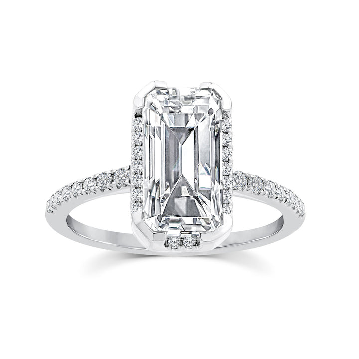 An emerald-cut diamond ring with a halo setting and a pavé-set diamond band, shown on a clean white background.