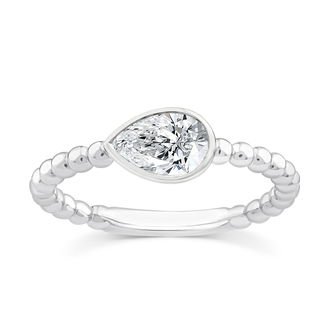 A silver ring featuring a marquise-cut clear gemstone in a bezel setting, with a beaded band, shown on a plain white background.