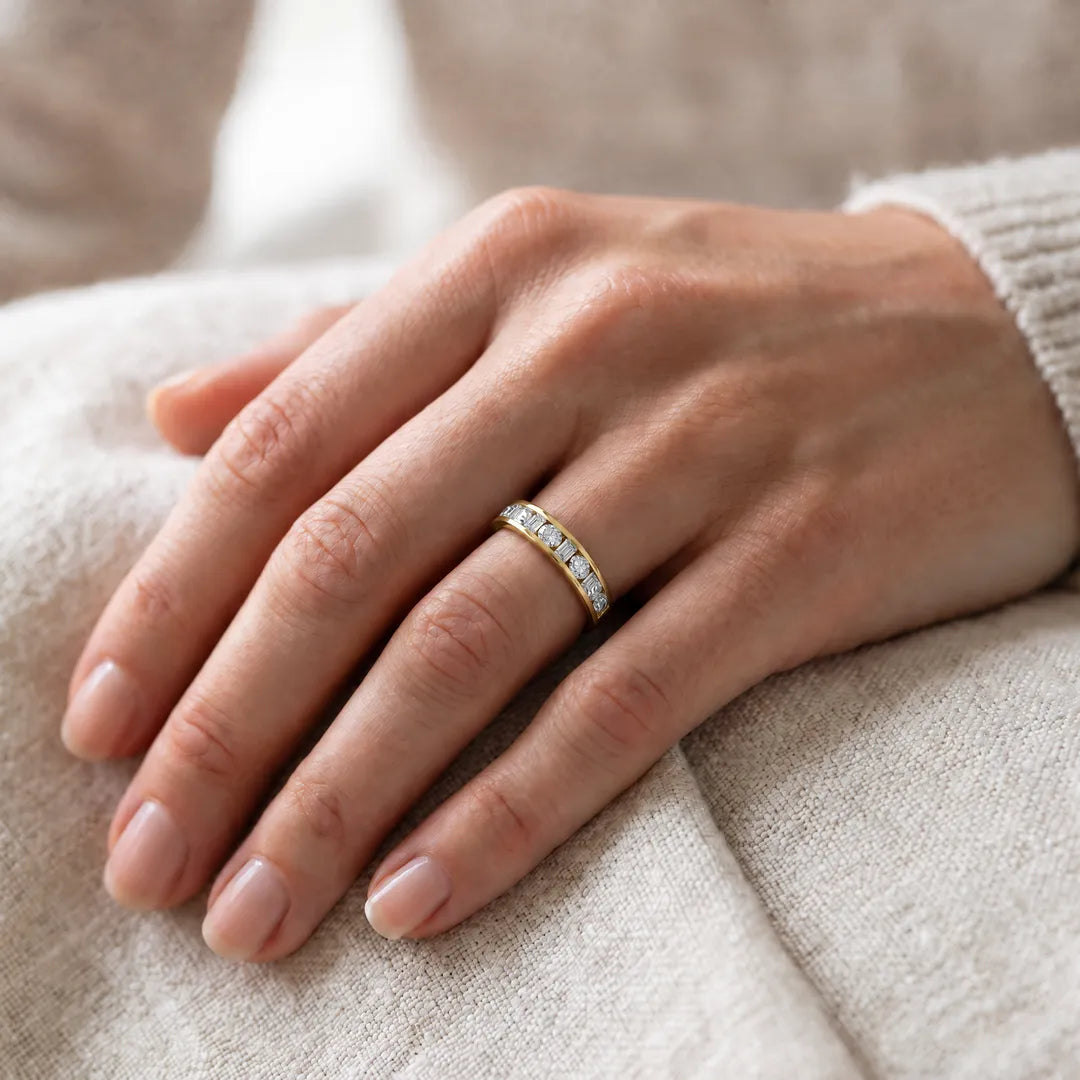 1.50ct emerald and round lab grown diamond channel-set ring in 9K yellow gold worn on a model's hand