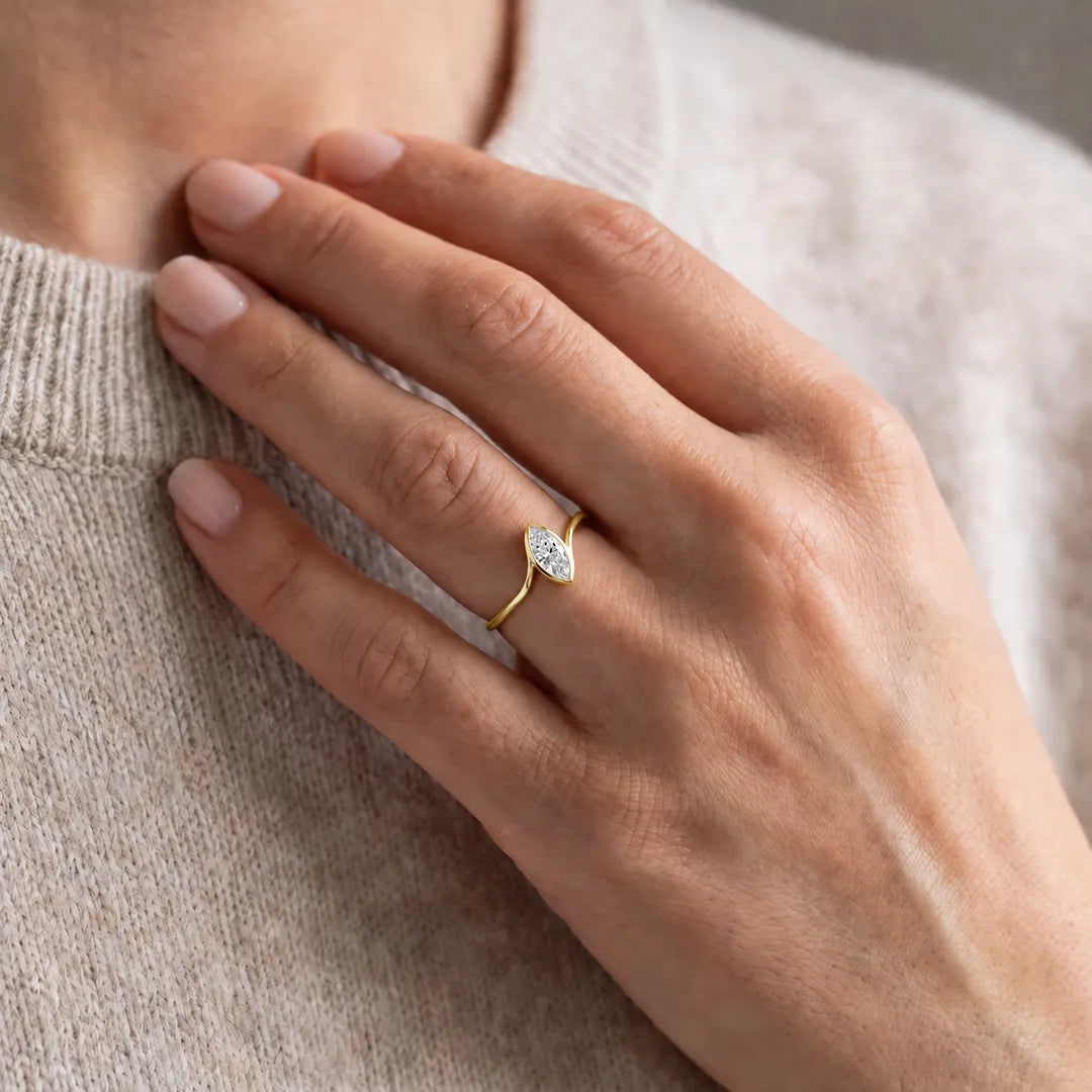 1.00ct marquise lab grown diamond bezel-set accent ring in 9K yellow gold worn on a model's hand