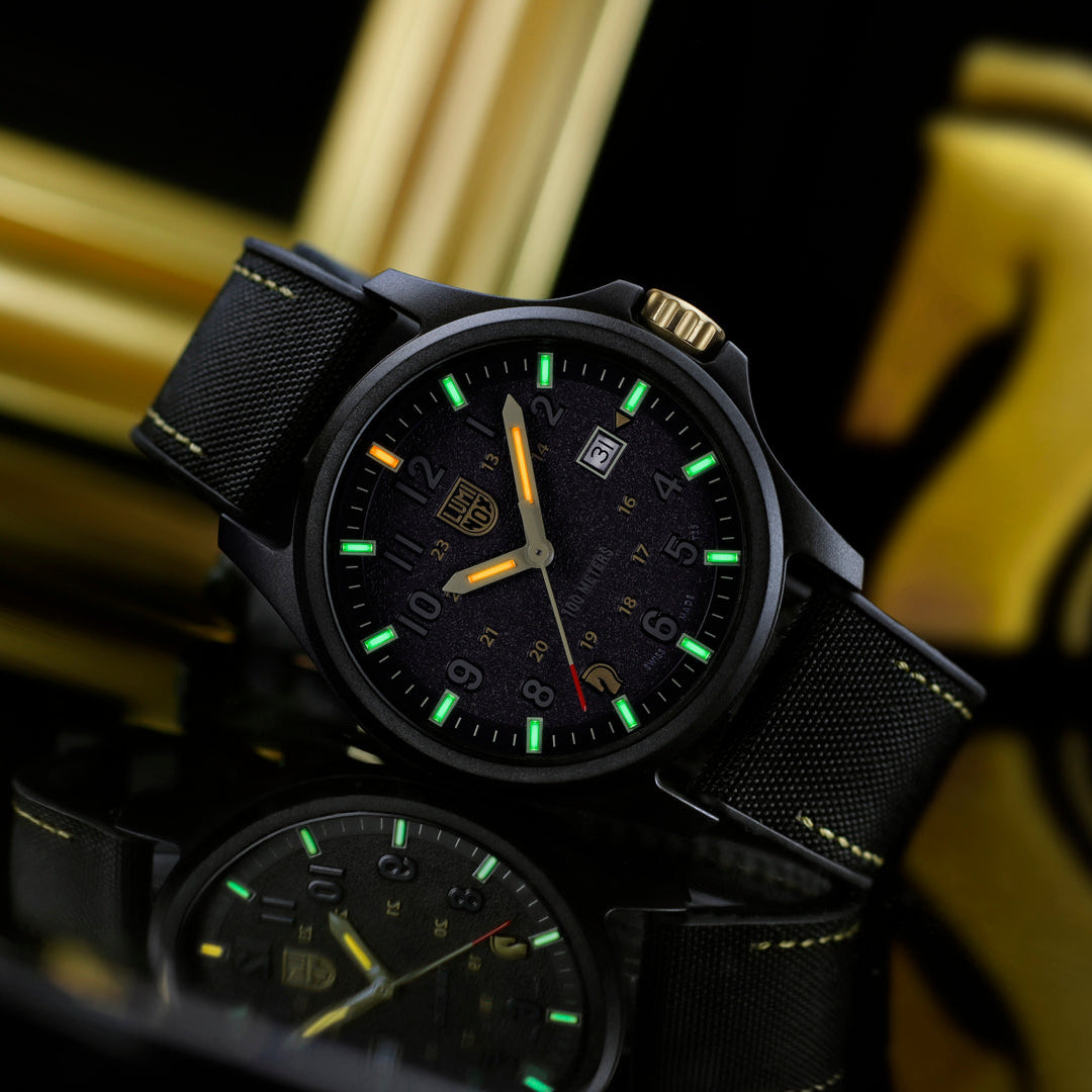 Black watch with green accents on a reflective surface, gold background